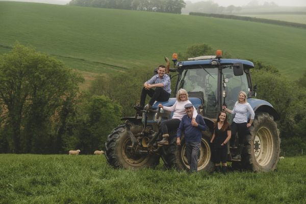 The Winzer family on the New Holland tractor at Higher Coarsewell with sheep in the field behind